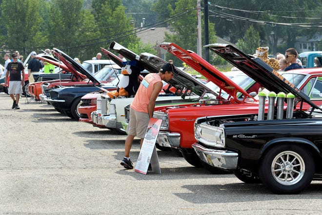 Onlookers look over classic cars parked in a lot next to the McLaren-Macomb building during the 18th annual Clinton Township Gratiot Cruise, Sunday, Aug. 1, 2021 in Clinton Township, Mich.