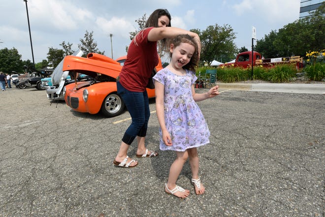 Mary Reinhardt of Sterling Heights dances with her daughter, Riley Taylor, age 6, during the 18th annual Clinton Township Gratiot Cruise, Sunday, Aug. 1, 2021 in Clinton Township, Mich.