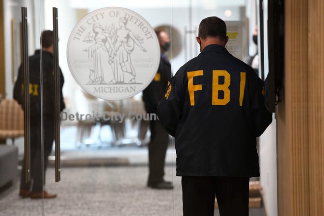 An FBI employee guards the front entrance doors to Detroit City Council on the 13th floor, Wednesday, Aug. 25, 2021 in Detroit.