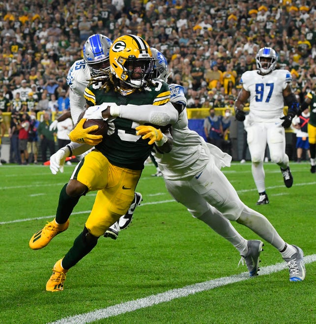 Packers' Aaron Jones takes Lions' Tracy Walker into the end zone for a touchdown in the second quarter.