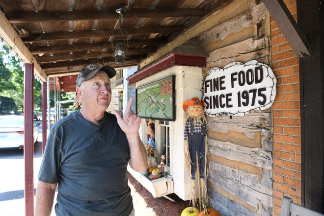 Mike Cummins, 65, of Glendale, talks about the small log cabin that was moved to Main Street in the 80s and attached to The Whistle Stop, right, in Glendale, Kentucky, on Sept. 27, 2021.  Cummins is semi-retired and recently sold The Whistle Stop, a staple of the area.