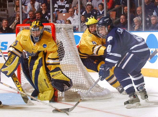 New Hampshire's Steve Saviano, right, is checked by Michigan's Andy Burnes as Michigan goalie Al Montoya prepares for a shot during a 2004 NCAA Northeast Regional tournament game in Manchester, N.H.