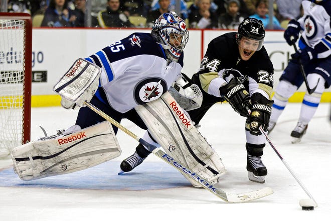 Winnipeg Jets goalie Al Montoya, left, makes a save on Pittsburgh Penguins forward Matt Cooke during the second period of an NHL game in 2013 in Pittsburgh.