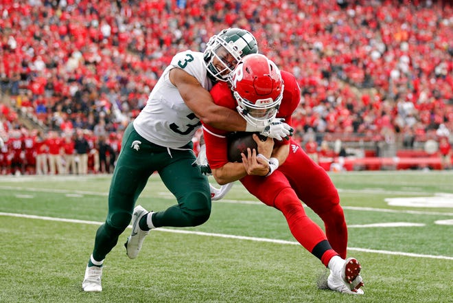 Michigan State safety Xavier Henderson, left, tackles Rutgers quarterback Noah Vedral during the first half.