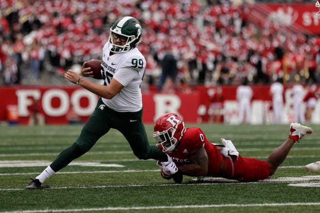 Michigan State punter Bryce Baringer (99) is tackled by Rutgers defensive back Christian Izien (0) during the first half.