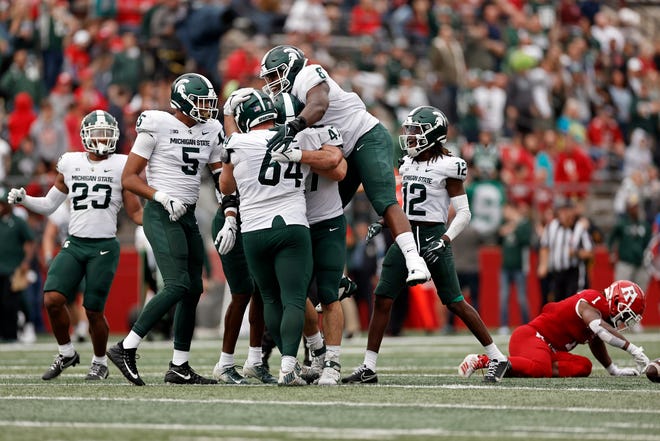 Michigan State defensive tackle Simeon Barrow (8) jumps on Jacob Slade (64) after Slade recovered a fumble against Rutgers during the second half.