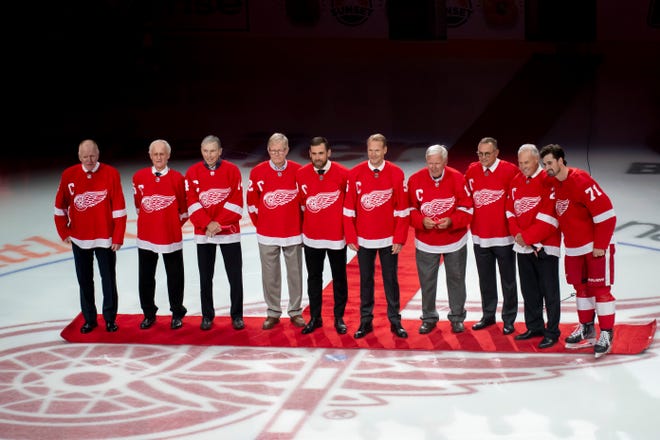 From left, former and current Red Wings captains Red Berenson, Paul Woods, Nick Libett, Dennis Hextall, Henrik Zetterberg, Nick Lidstrom, Alex Delvecchio, Steve Yzerman, Mickey Redmond, and Dylan Larkin stand together before the start of the home opener against the Tampa Bay Lightning on Thursday, Oct. 14, 2021, at Little Caesars Arena in Detroit.