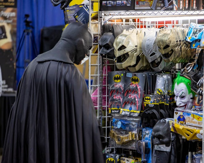 A man dressed as Batman looks at Batman stuff for sale during the Motor City Comic Con.