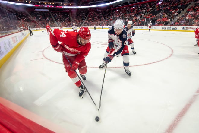 Detroit center Robby Fabbri and Columbus defenseman Zach Werenski battle for the puck along the boards during the third period of a game between the Detroit Red Wings and the Columbus Blue Jackets at Little Caesars Arena, in Detroit, October 19, 2021.
