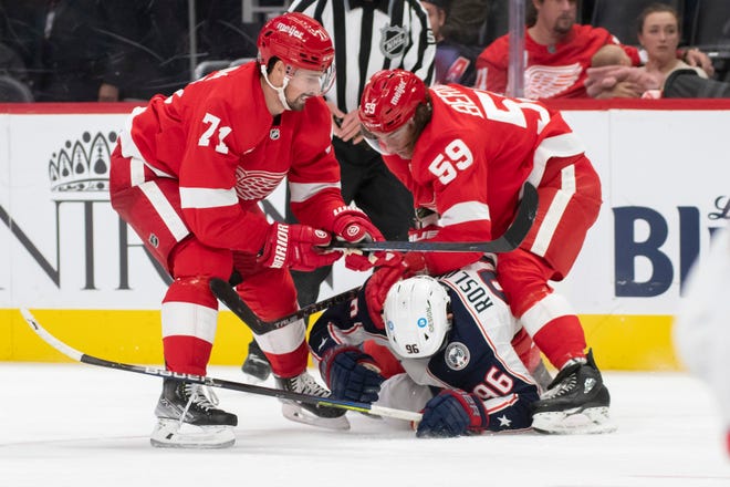 Detroit center Dylan Larkin, left, and left wing Tyler Bertuzzi go after Columbus center Jack Roslovic after a hit on Detroit left wing Lucas Raymond during the third period of a game between the Detroit Red Wings and the Columbus Blue Jackets at Little Caesars Arena, in Detroit, October 19, 2021.