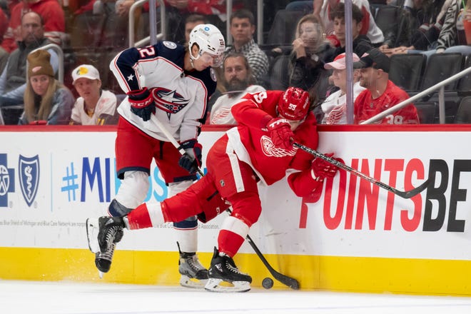 Detroit left wing Tyler Bertuzzi and Columbus defenseman Jake Bean battle for the puck along the boards during the third period of a game between the Detroit Red Wings and the Columbus Blue Jackets at Little Caesars Arena, in Detroit, October 19, 2021.