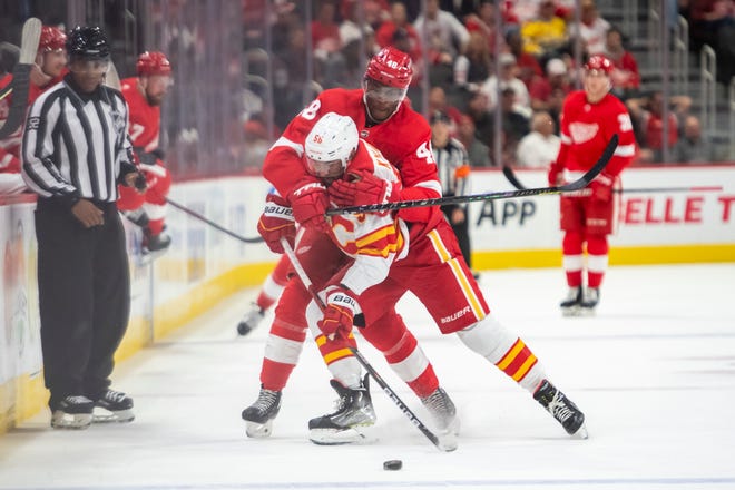 Detroit right wing Givani Smith wraps up Calgary defenseman Oliver Kylington while battling for the puck during the first period of a game between the Detroit Red Wings and the Calgary Flames, at Little Caesars Arena, in Detroit, October 21, 2021.