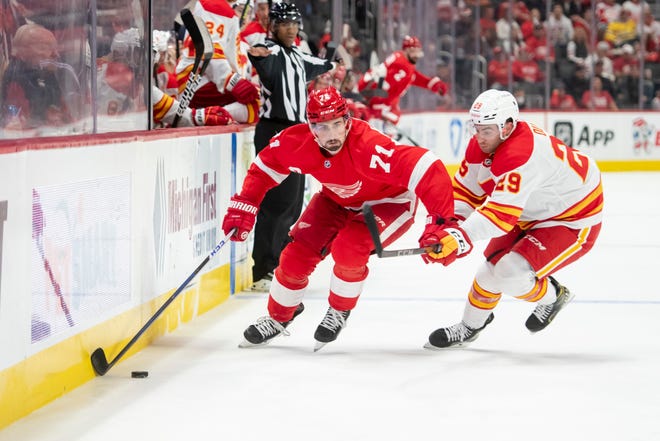 Detroit center Dylan Larkin tries to keep the puck away from Calgary center Dillon Dube during the first period of a game between the Detroit Red Wings and the Calgary Flames, at Little Caesars Arena, in Detroit, October 21, 2021.
