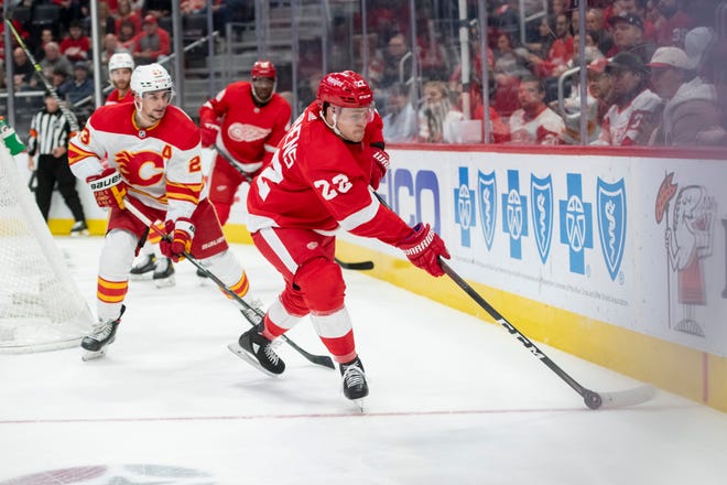 Detroit center Mitchell Stephens keeps the puck away from Calgary center Sean Monahan during the first period of a game between the Detroit Red Wings and the Calgary Flames, at Little Caesars Arena, in Detroit, October 21, 2021.