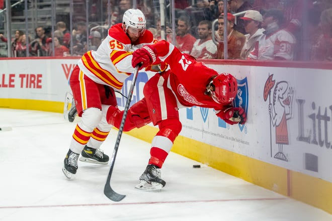 Calgary defenseman Noah Hanifin shoves Detroit center Michael Rasmussen into the boards during the first period of a game between the Detroit Red Wings and the Calgary Flames, at Little Caesars Arena, in Detroit, October 21, 2021.