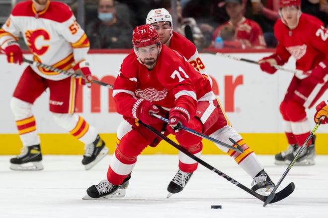 Detroit center Dylan Larkin keeps the puck away from Calgary center Dillon Dube during the second period of a game between the Detroit Red Wings and the Calgary Flames, at Little Caesars Arena, in Detroit, October 21, 2021.