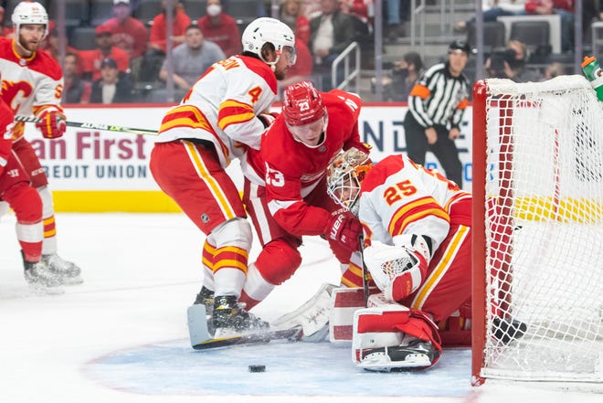 Detroit left wing Lucas Raymond tries to get the puck past Calgary defenseman Rasmus Andersson and right wing Brad Richardson during the first period of a game between the Detroit Red Wings and the Calgary Flames, at Little Caesars Arena, in Detroit, October 21, 2021.