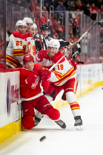 Detroit left wing Lucas Raymond is checked by Calgary left wing Matthew Tkachuk during the third period of a game between the Detroit Red Wings and the Calgary Flames, at Little Caesars Arena, in Detroit, October 21, 2021.