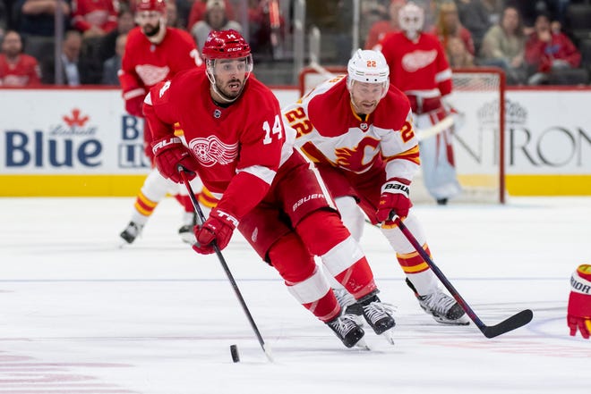 Detroit center Robby Fabbri moves the puck away from Calgary center Trevor Lewis during the third period of a game between the Detroit Red Wings and the Calgary Flames, at Little Caesars Arena, in Detroit, October 21, 2021.
