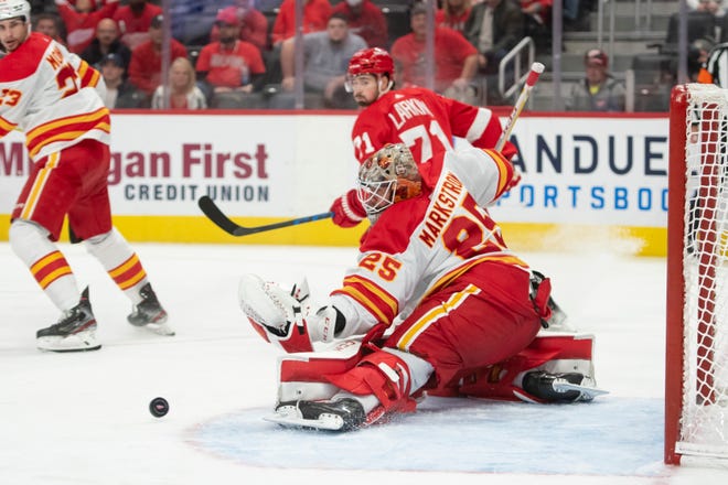 Calgary goaltender Jacob Markstrom makes a save in front of Detroit center Dylan Larkin during the third period of a game between the Detroit Red Wings and the Calgary Flames, at Little Caesars Arena, in Detroit, October 21, 2021.
