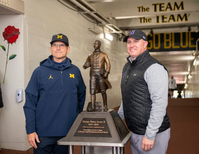 Michigan coach Jim Harbaugh, left, and Northwestern coach Pat Fitzgerald pose next to the George Jewett Trophy before the game. The trophy is the first in the Football Bowl Subdivision to honor an African-American. Jewett is an alumnus of both universities and was the first Black football player at each school.