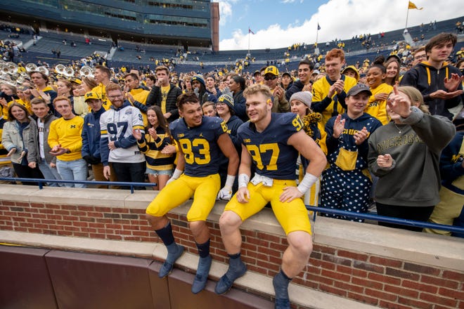 Michigan tight end Erick All, left, and defensive end Aidan Hutchinson celebrate with the fans after the game.