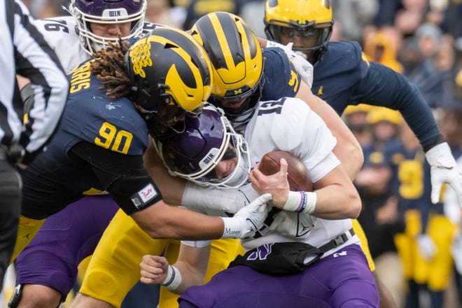 Northwestern quarterback Ryan Hilinski is sacked by Michigan defensive ends Mike Morris, left, and Aidan Hutchinson during the second quarter of a game at Michigan Stadium in Ann Arbor on Saturday, Oct. 23, 2021. Michigan won, 33-7.