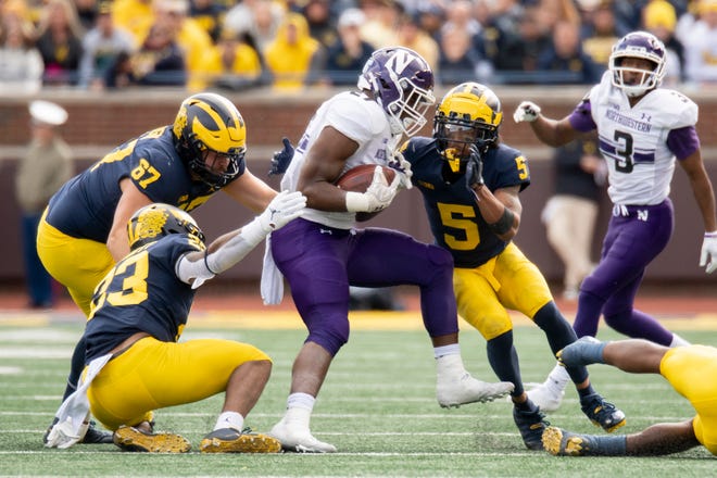 Northwestern running back Anthony Tyus III is tackled by, from left, Michigan defensive lineman Jess Speight, linebacker Michael Barrett, and defensive back DJ Turner during the fourth quarter.