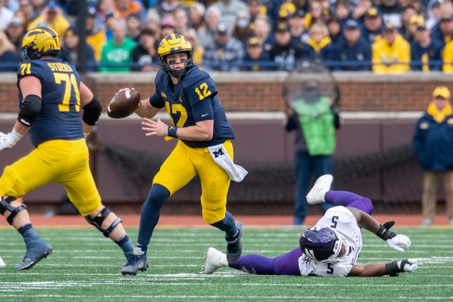 Michigan quarterback Cade McNamara looks for an open man while evading a tackle by Northwestern defensive lineman Jeffery Pooler Jr. during the second quarter.