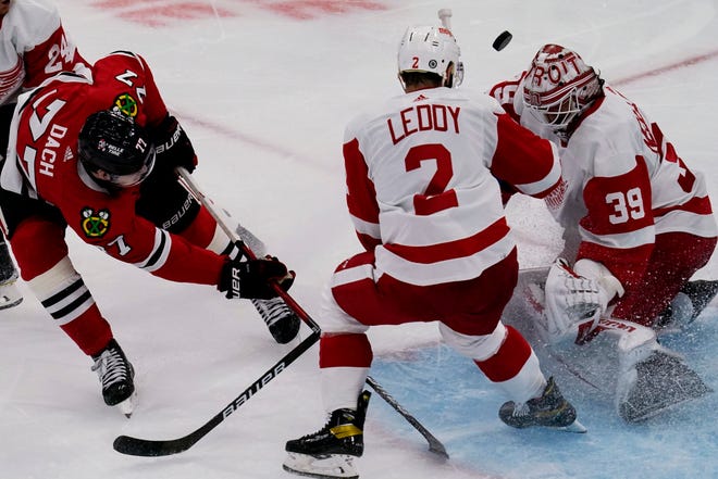 Red Wings goaltender Alex Nedeljkovic, right, makes a save on a shot by Blackhawks center Kirby Dach, left, as Red Wings defenseman Nick Leddy watches during the second period.
