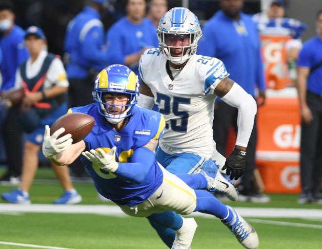 Rams' Tyler Higbee stretches out in front of Lions' Will Harris on a throw that eventually, after review, was called an incomplete pass in the third quarter.
