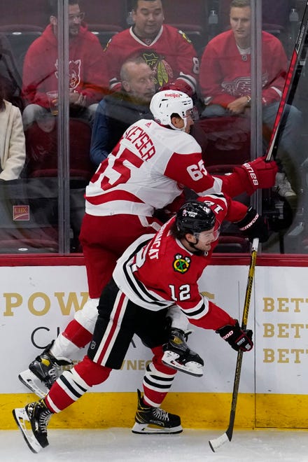 Red Wings defenseman Danny DeKeyser, left, is checked by Blackhawks left wing Alex DeBrincat during the first period.