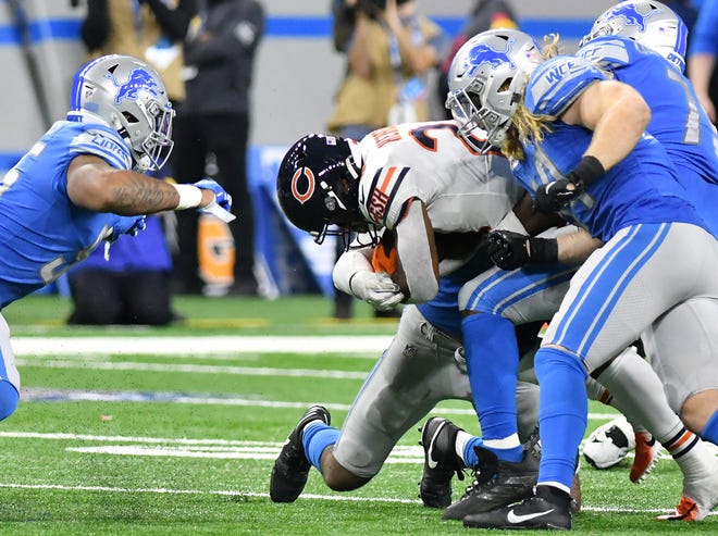 Lions inside linebackers Alex Anzalone (34) and Derrick Barnes, left, tackle Bears running back Khalil Herbert (24) in the fourth quarter.