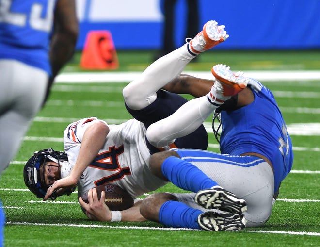 Bears quarterback Andy Dalton is dragged down by Lions' Austin Bryant in the third quarter.