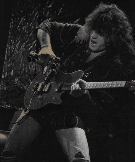 Eddie Van Halen uses a hand drill as a slide bar for his guitar during a performance at the Pine Knob Music Theater in Clarkston, Mich. in 1991.