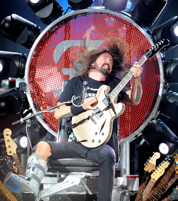 Foo Fighters singer/guitarist David Grohl performs while sitting to help him out with his broken leg at DTE Energy Music Theater in Clarkston, on Aug. 24, 2015.