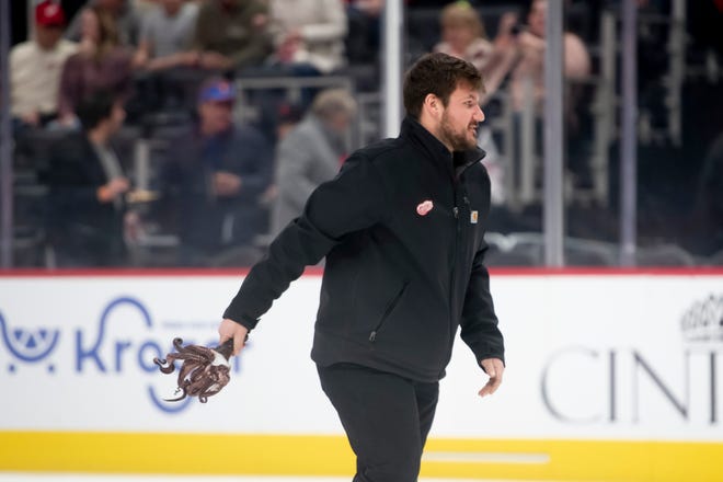 A member of the ice crew picks up an octopus that had been thrown onto the ice before the start of a game between the Detroit Red Wings and the Winnipeg Jets.