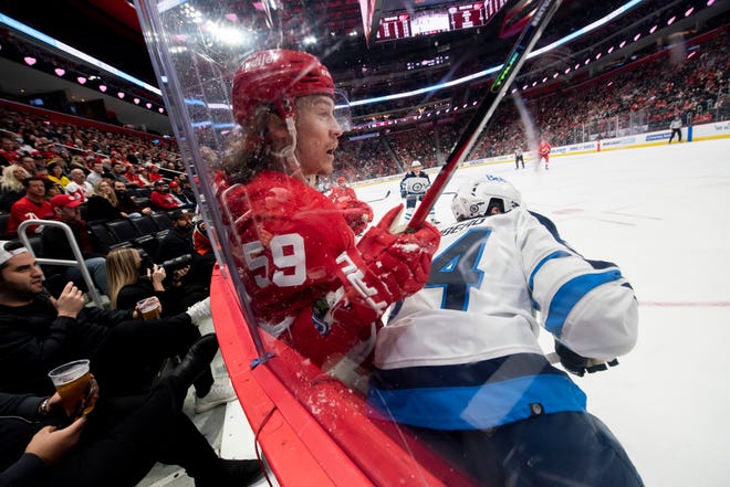 Detroit left wing Tyler Bertuzzi is checked by Winnipeg defenseman Dylan Samberg during the first period at Little Caesars Arena, in Detroit, January 13, 2022.