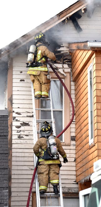 Firefighters fight the fire while standing on a ladder on Friday, Jan. 14, 2022.