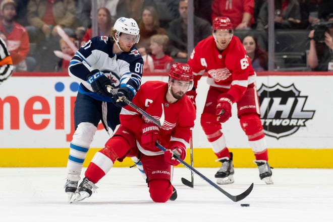 Detroit center Dylan Larkin keeps the puck away from Winnipeg left wing Kyle Connor during the third period.