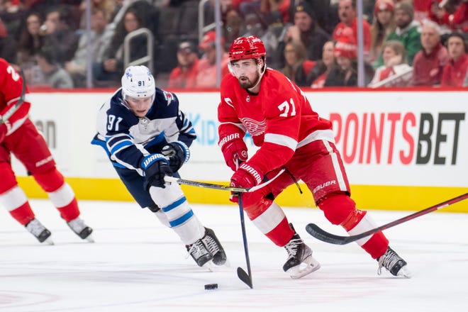 Detroit center Dylan Larkin keeps the puck away from Winnipeg center Cole Perfetti during the first period.