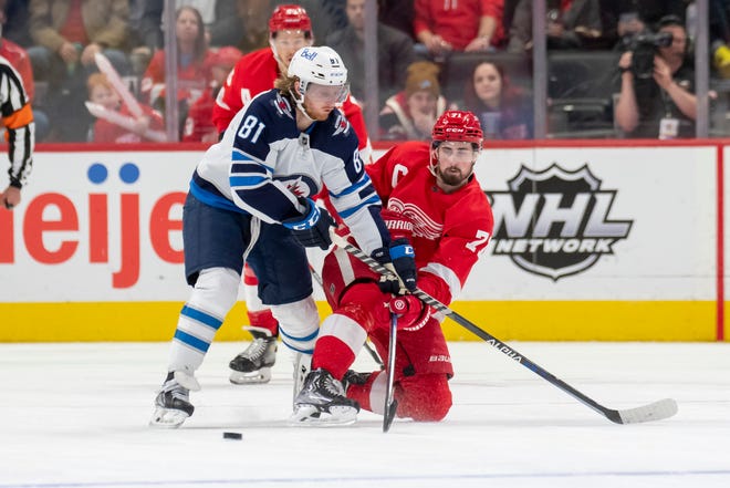 Detroit center Dylan Larkin keeps the puck away from Winnipeg left wing Kyle Connor during the third period.