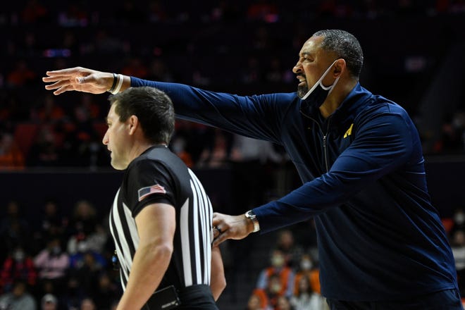 Michigan's coach Juwan Howard, right, grabs the arm of referee Kelly Pfeifer during the first half.