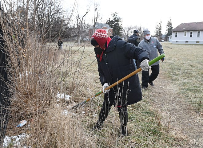 Mary Waters, Detroit councilwoman at large, rakes debris in a vacant lot adjacent the Greenhouse Senior Apartments on the Southfield service drive in Detroit as part of MLK Day of Service activities on Jan. 17, 2022.