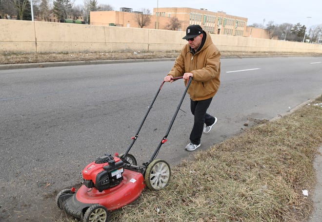 John J. George, executive director of Detroit Blight Busters, mows grass in front of Greenhouse Senior Apartments on the Southfield service drive in Detroit during a day of service to honor the Rev. Martin Luther King, on January 17, 2022, in Detroit, Michigan.