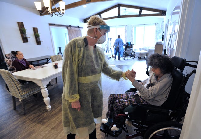 Pioneer Resources CEO Jill Bonthuis, left, shakes hands with resident Jan Parker, Wed. Jan. 19, 2022, before Parker takes a nap after lunch and the CEO leaves the facility.