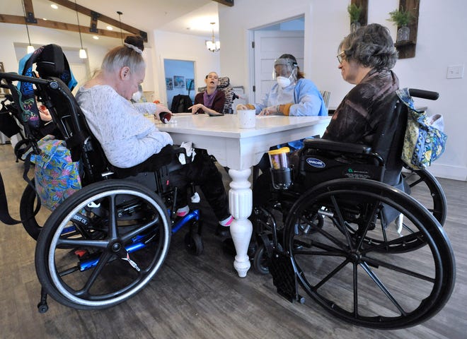 Residents Jeannie Shields, left, and Barbara Bennett, right, play Yahtzee with resident-support-staff worker Africa Sydnor, center-right, as resident Kimberly Mueller, center-left, watches, Wed. Jan. 19, 2022.