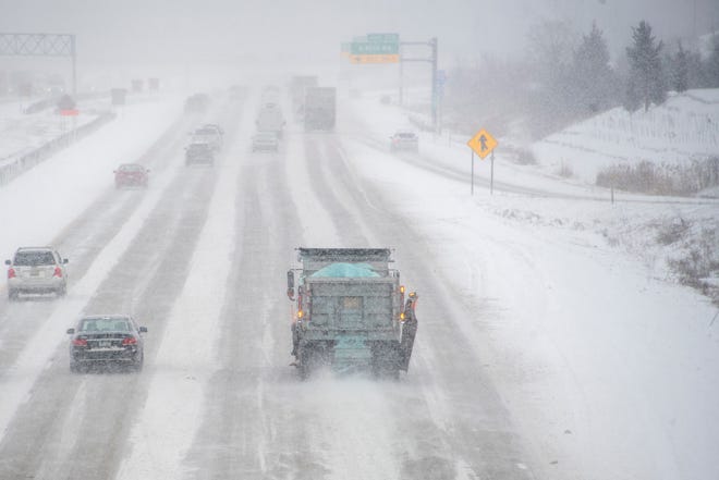 A salt truck makes its way down a snow covered I-275 freeway near 7 Mile Road in Livonia, Monday.