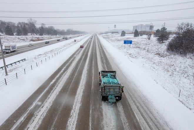A salt truck makes its way down a snow covered I-275 freeway near 7 Mile Road in Livonia, January 24, 2022. (David Guralnick / The Detroit News)