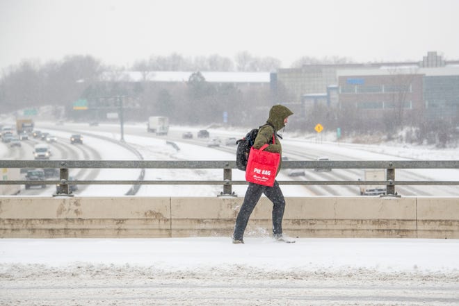 A man makes his way across a snow covered 7 Mile Road bridge over the I-275 freeway in Livonia, January 24, 2022.